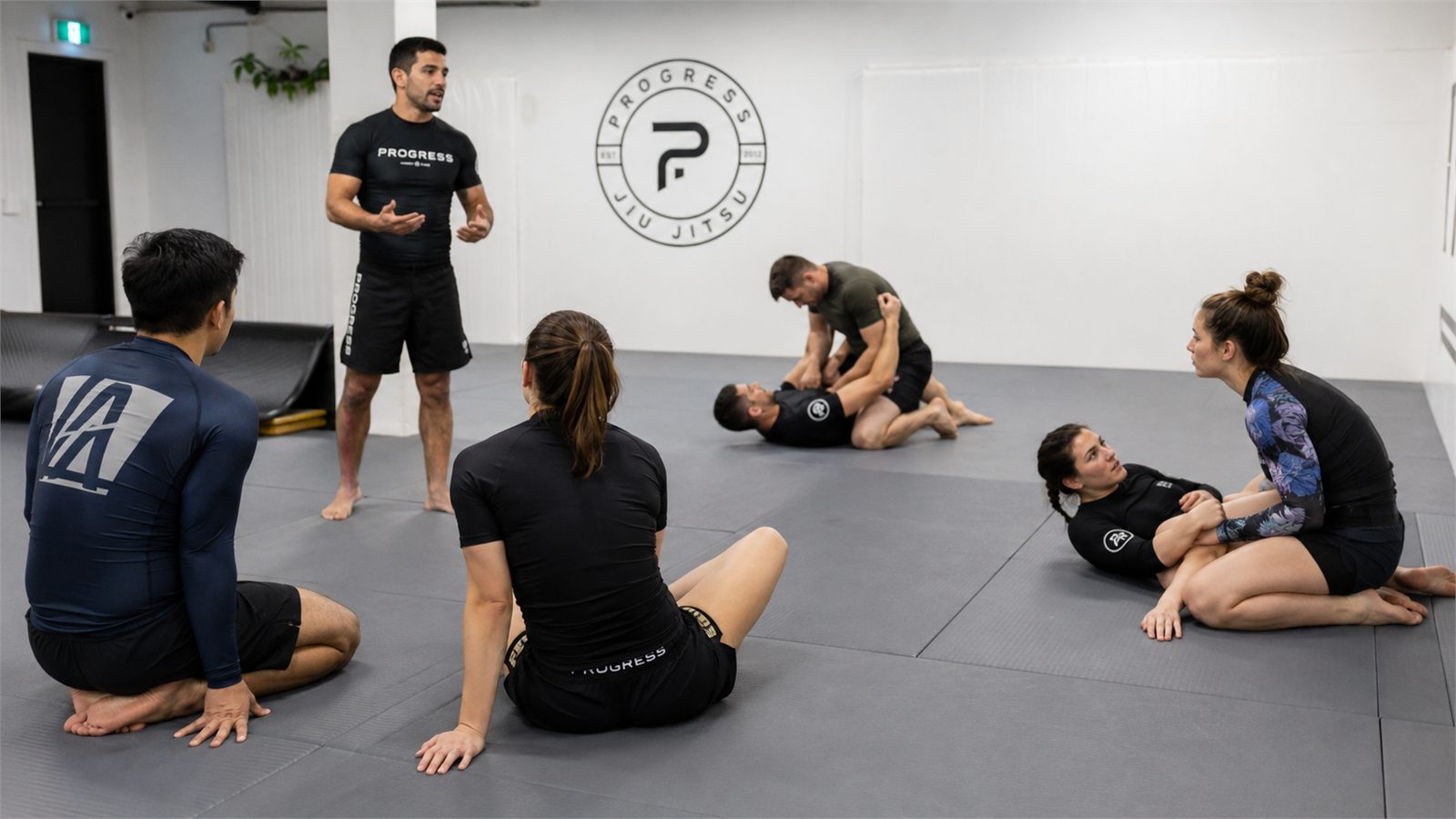 Students sitting on the mat listening to the coach before drilling.