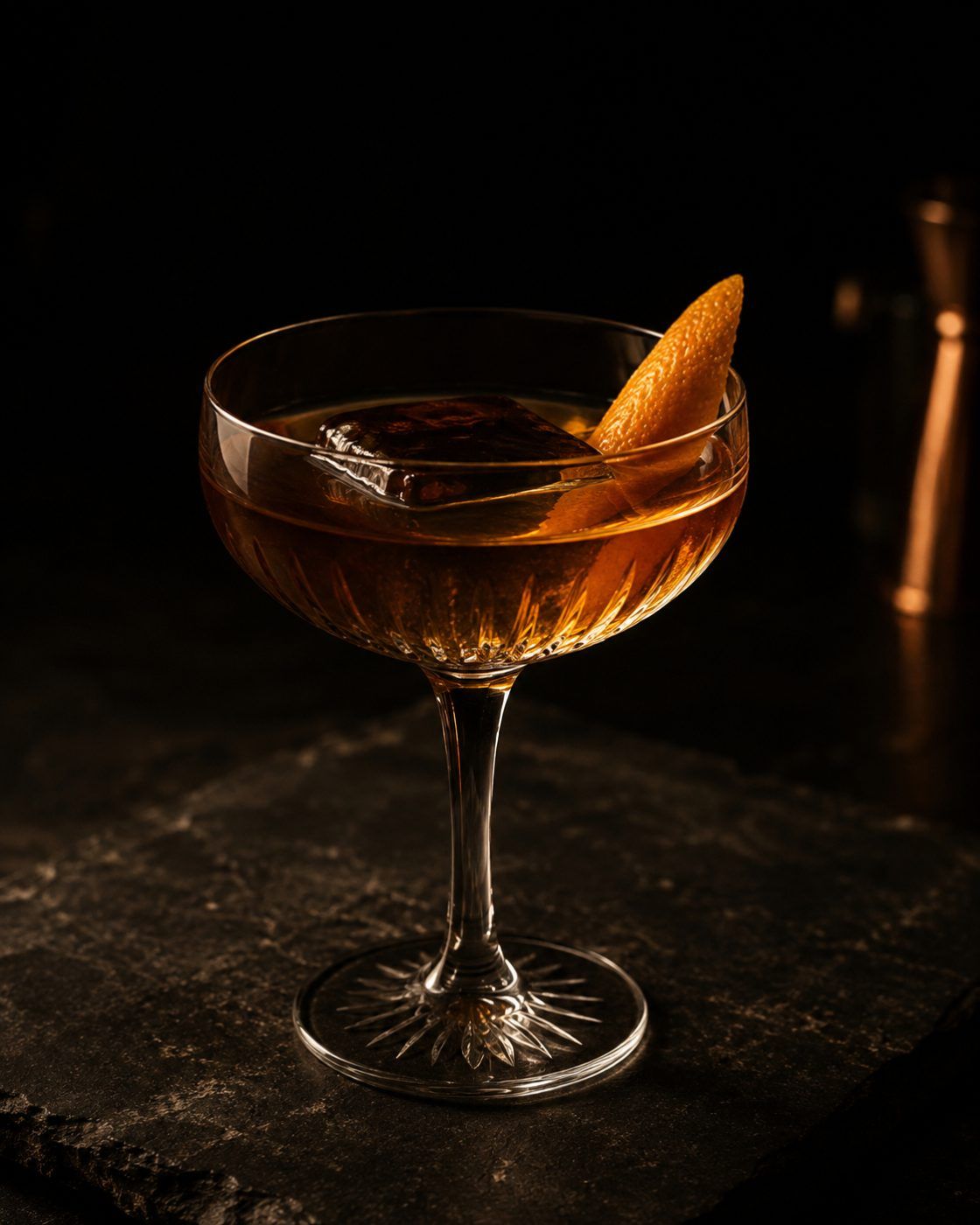 A cocktail in a coupe glass finished with citrus peel